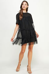 woman wearing a black tiered tulle dress with short sleeves and a relaxed fit