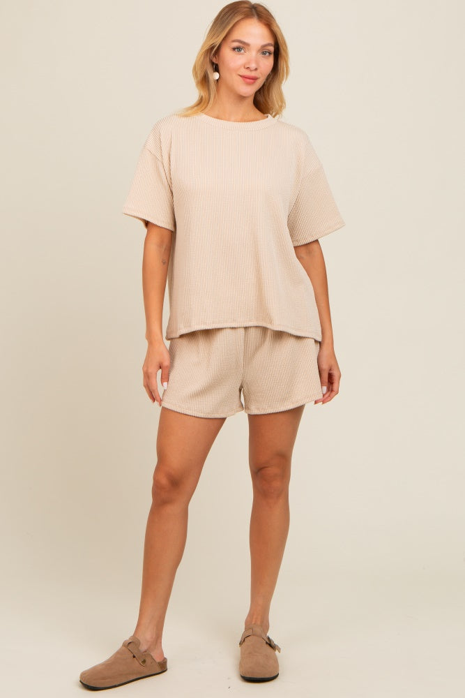 woman wearing a beige ribbed knit short sleeve top with matching shorts and brown slip-on shoes