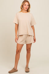 woman wearing a beige ribbed knit short sleeve top with matching shorts and brown slip-on shoes