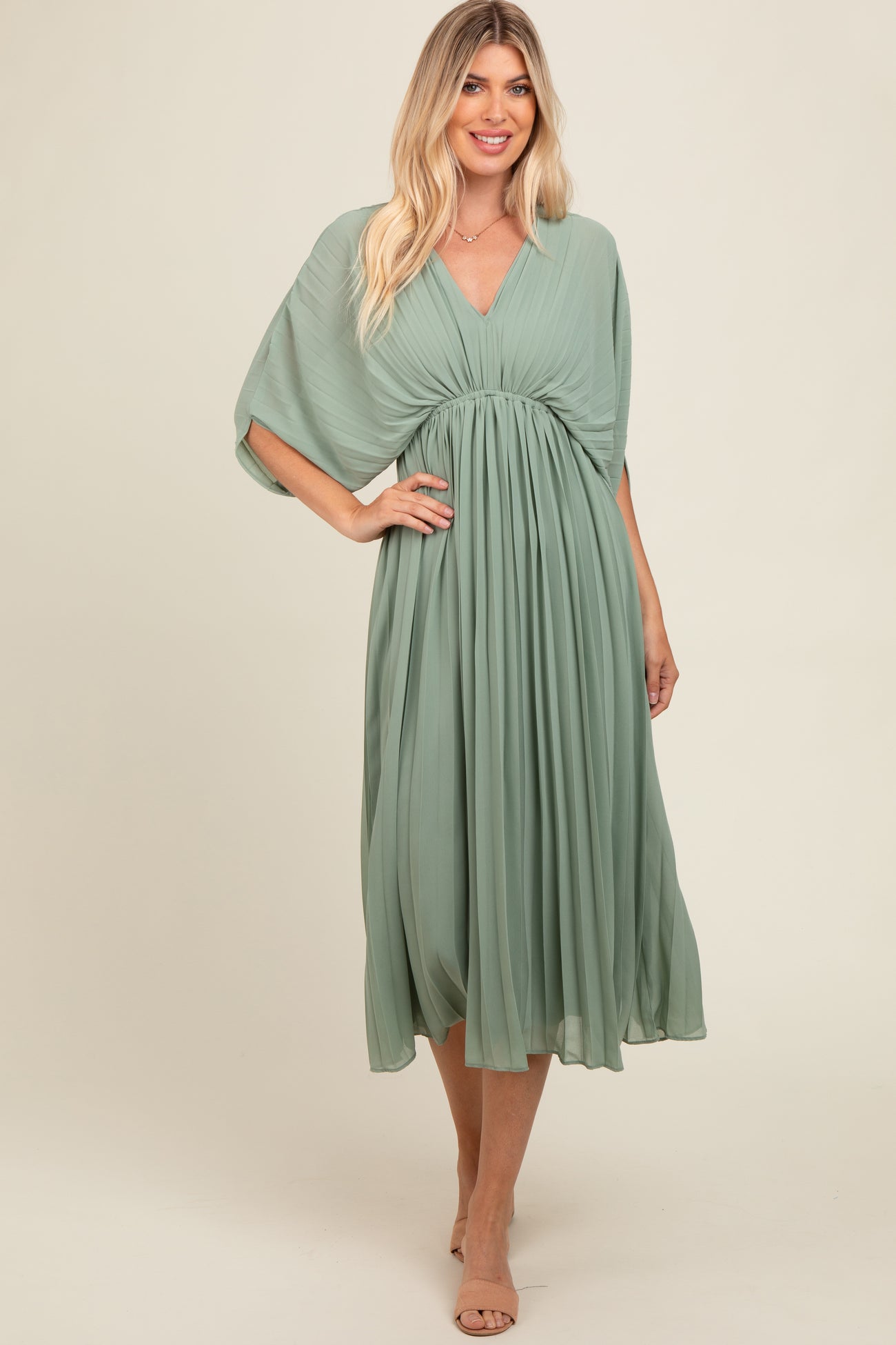 woman wearing a flowy sage green midi dress with a wrap-style top and gathered waist