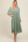 woman wearing a flowy sage green midi dress with a wrap-style top and gathered waist