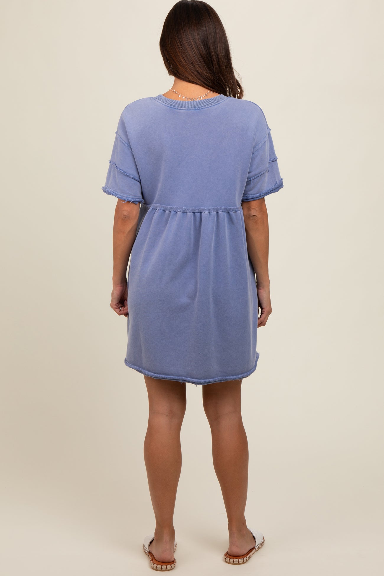 woman wearing a light blue short sleeve maternity dress with a relaxed fit and frayed hem