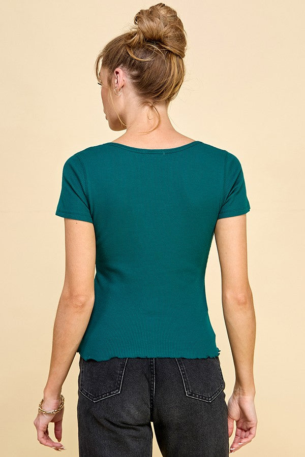 woman wearing a green short sleeve ribbed top with a scalloped hem, shown from the back