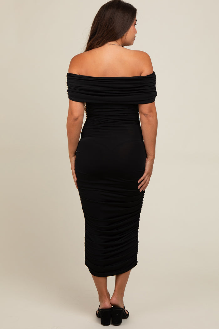 woman wearing a sleek black off-the-shoulder maternity dress with ruched detailing, showing a baby bump from the back