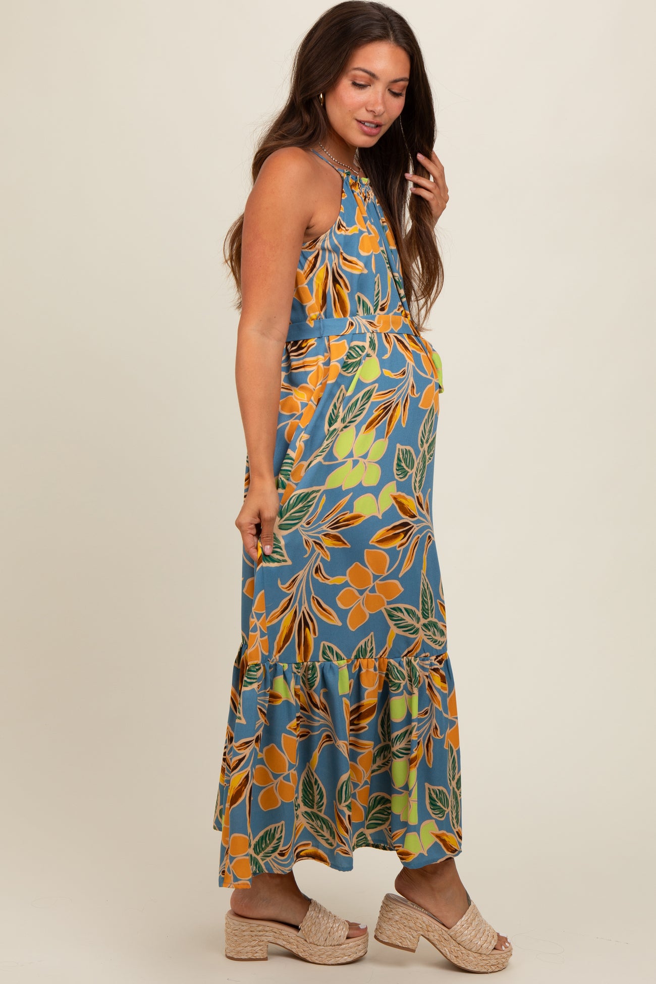 woman wearing a floral print maternity maxi dress with a ruffled hem and visible baby bump