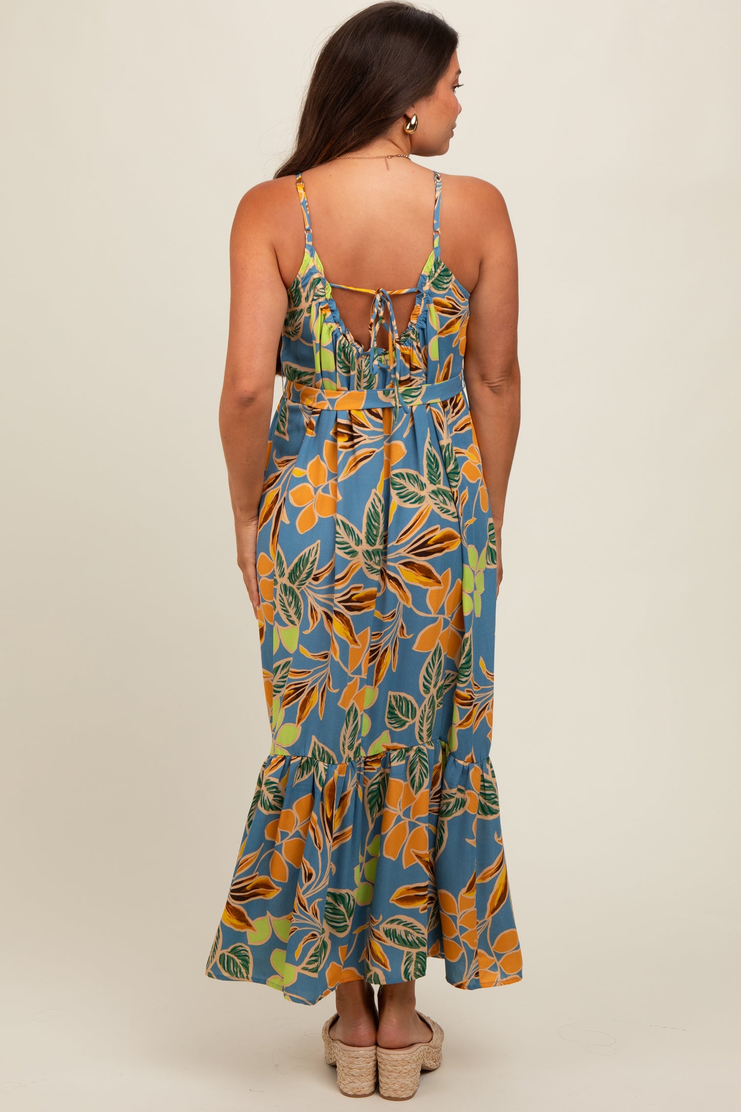 woman wearing a floral print maternity maxi dress with a tie-back detail and ruffled hem