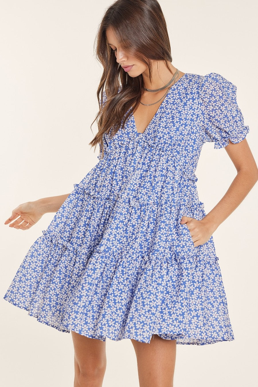 woman wearing a blue floral puff sleeve mini dress with a tiered skirt and a deep v-neckline