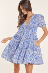 woman wearing a blue floral puff sleeve mini dress with a tiered skirt and a deep v-neckline