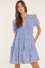 woman wearing a blue floral print tiered mini dress with puff sleeves and side pockets