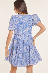 woman wearing a blue floral puff sleeve dress with a tiered skirt
