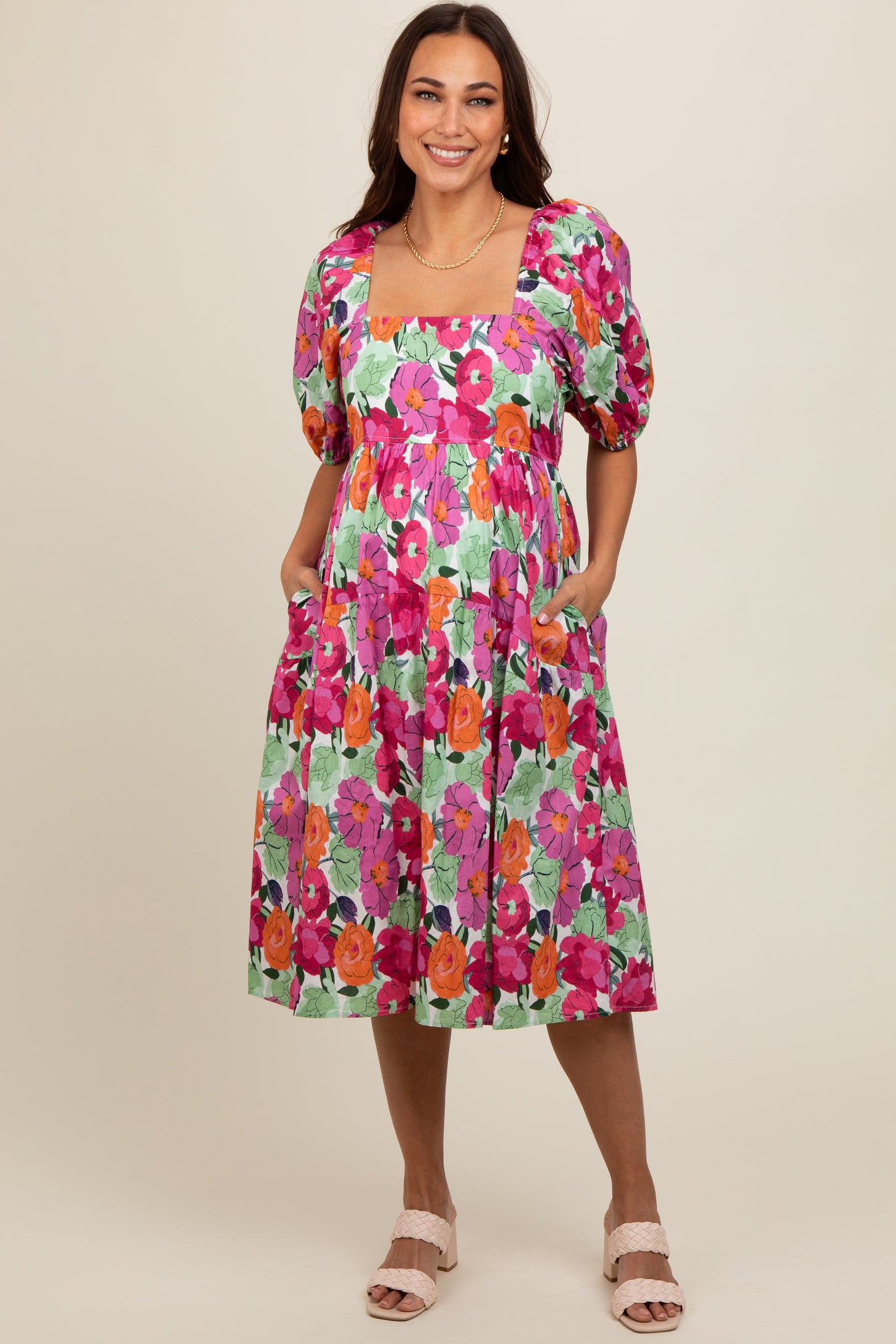 woman wearing a floral maternity dress with puff sleeves, pockets, and a square neckline, showcasing her baby bump