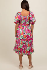 woman wearing a colorful floral maternity dress with puff sleeves and a smocked bodice, seen from the back