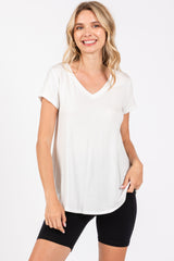 woman wearing a white short sleeve v-neck t-shirt and black biker shorts, smiling at the camera
