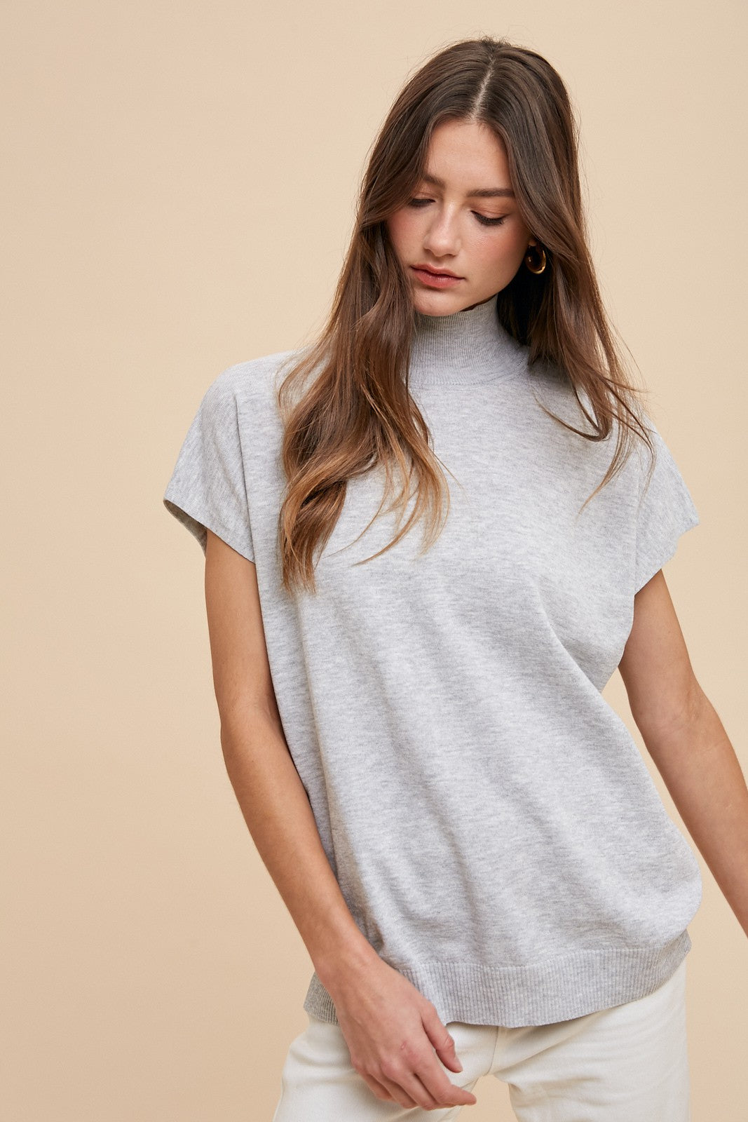 woman wearing a light gray short sleeve mock neck sweater with a relaxed fit