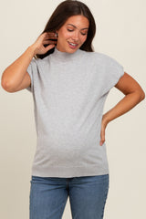 woman wearing a gray short sleeve maternity top and showing her baby bump while smiling