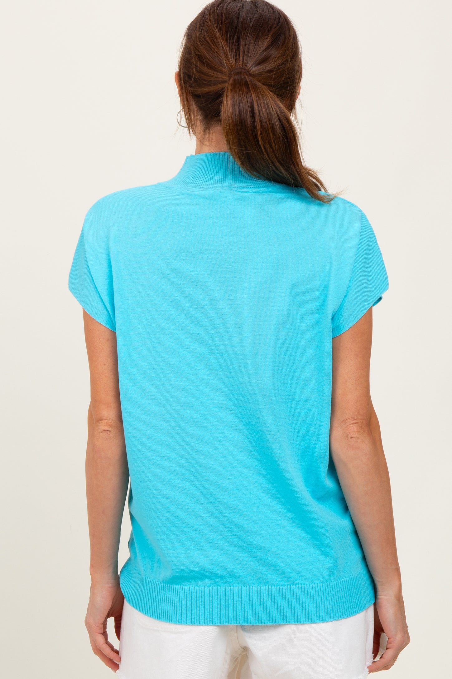 woman wearing a back view of a bright turquoise short sleeve knit top with a polo collar