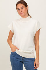 woman wearing a cream short sleeve turtleneck top with ribbed details and blue jeans