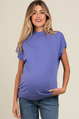 woman wearing a purple short sleeve maternity top with a visible baby bump and jeans