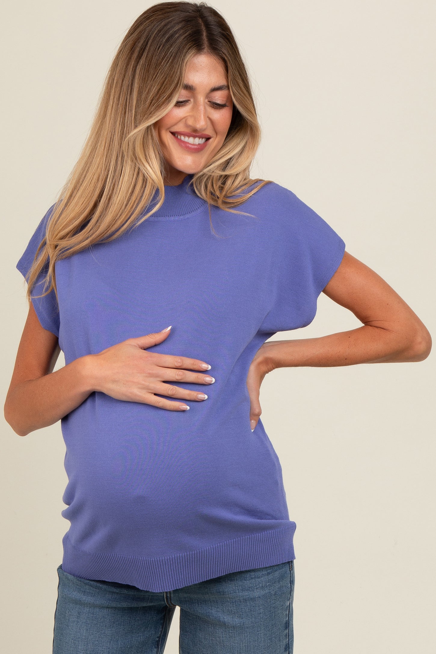 woman wearing a purple short sleeve maternity top and showing her baby bump