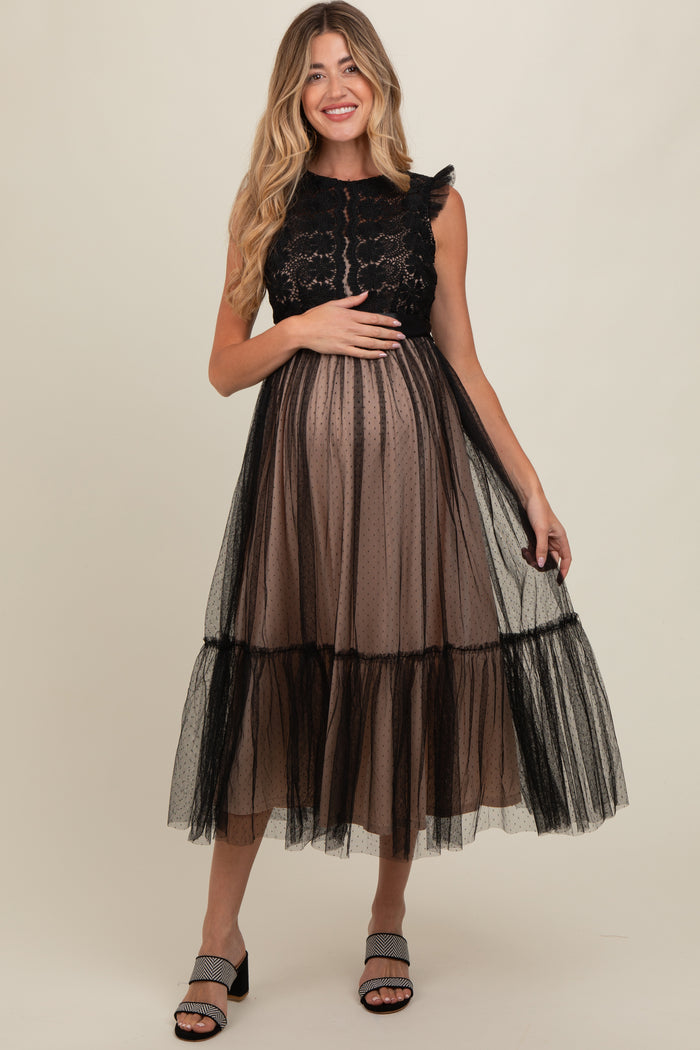 woman wearing a black lace and tulle maternity dress with a flowy skirt, holding her baby bump