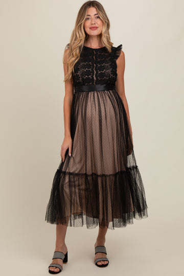 woman wearing a black lace maternity dress with a sheer skirt and ruffle details, showcasing her baby bump