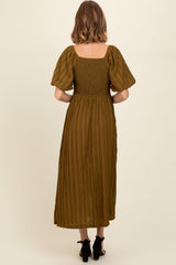 woman wearing a moss green smocked back midi dress with short puff sleeves and a flowing skirt