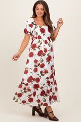 woman wearing a white floral maternity maxi dress with red roses and puff sleeves, showcasing her baby bump