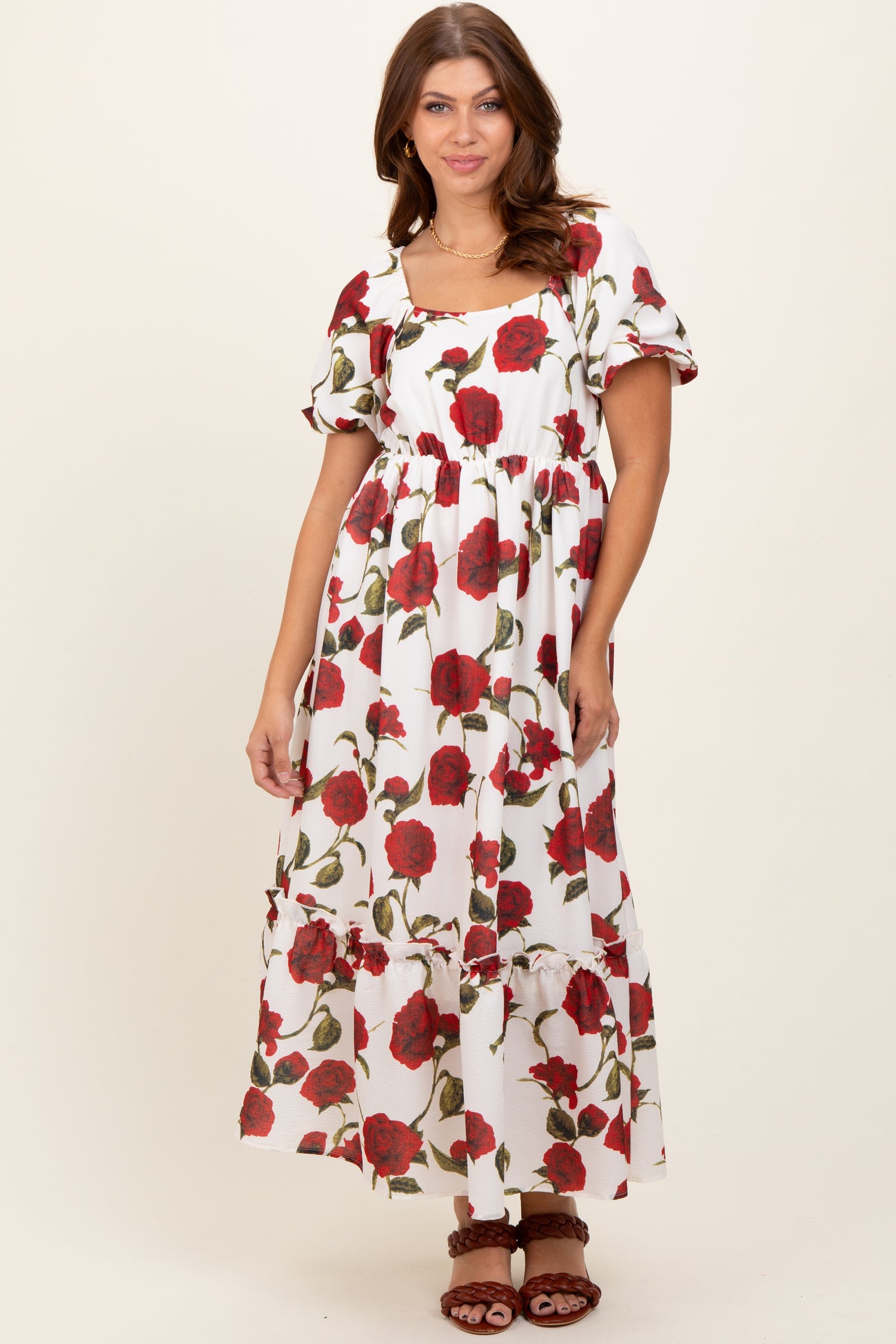 woman wearing a flowy white maxi dress with red floral print and puff sleeves