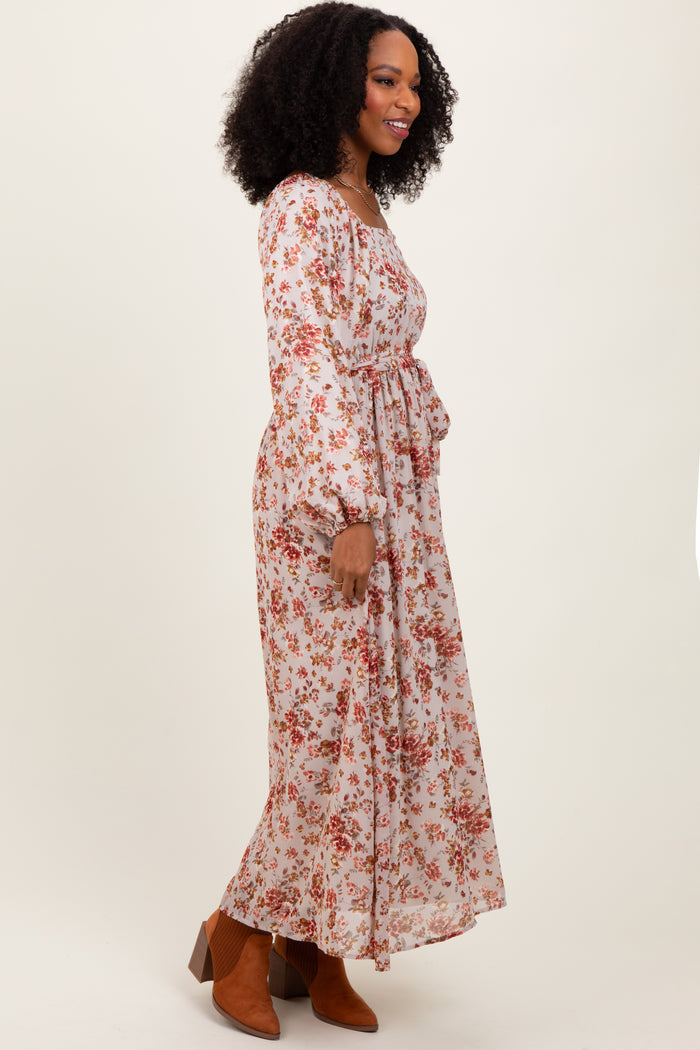 woman wearing a long sleeve floral maxi dress with a cinched waist and flowy silhouette, paired with ankle booties