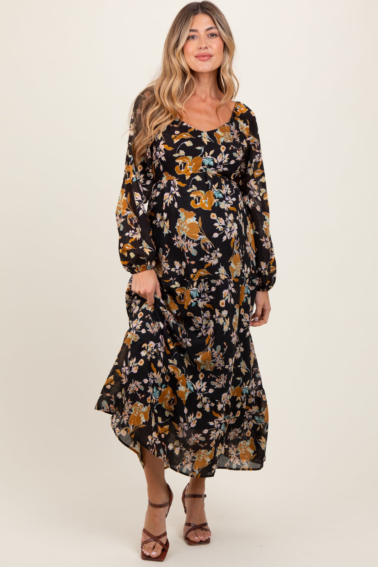 woman wearing a black floral long sleeve maternity dress with a flowing skirt and a square neckline, showing a baby bump