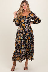 woman wearing a black floral maternity maxi dress with long sleeves and a fitted bodice, showing her baby bump