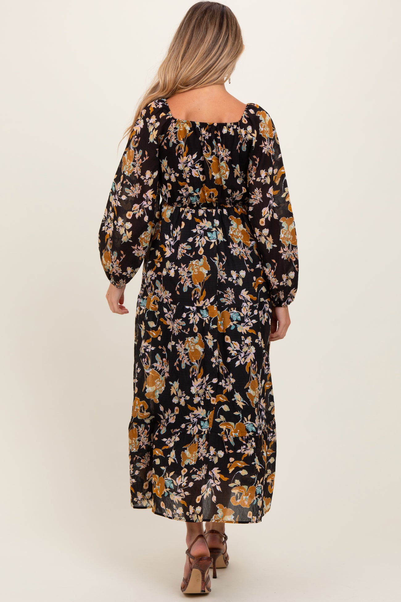 woman wearing a black floral maternity maxi dress with long puffed sleeves and a relaxed fit