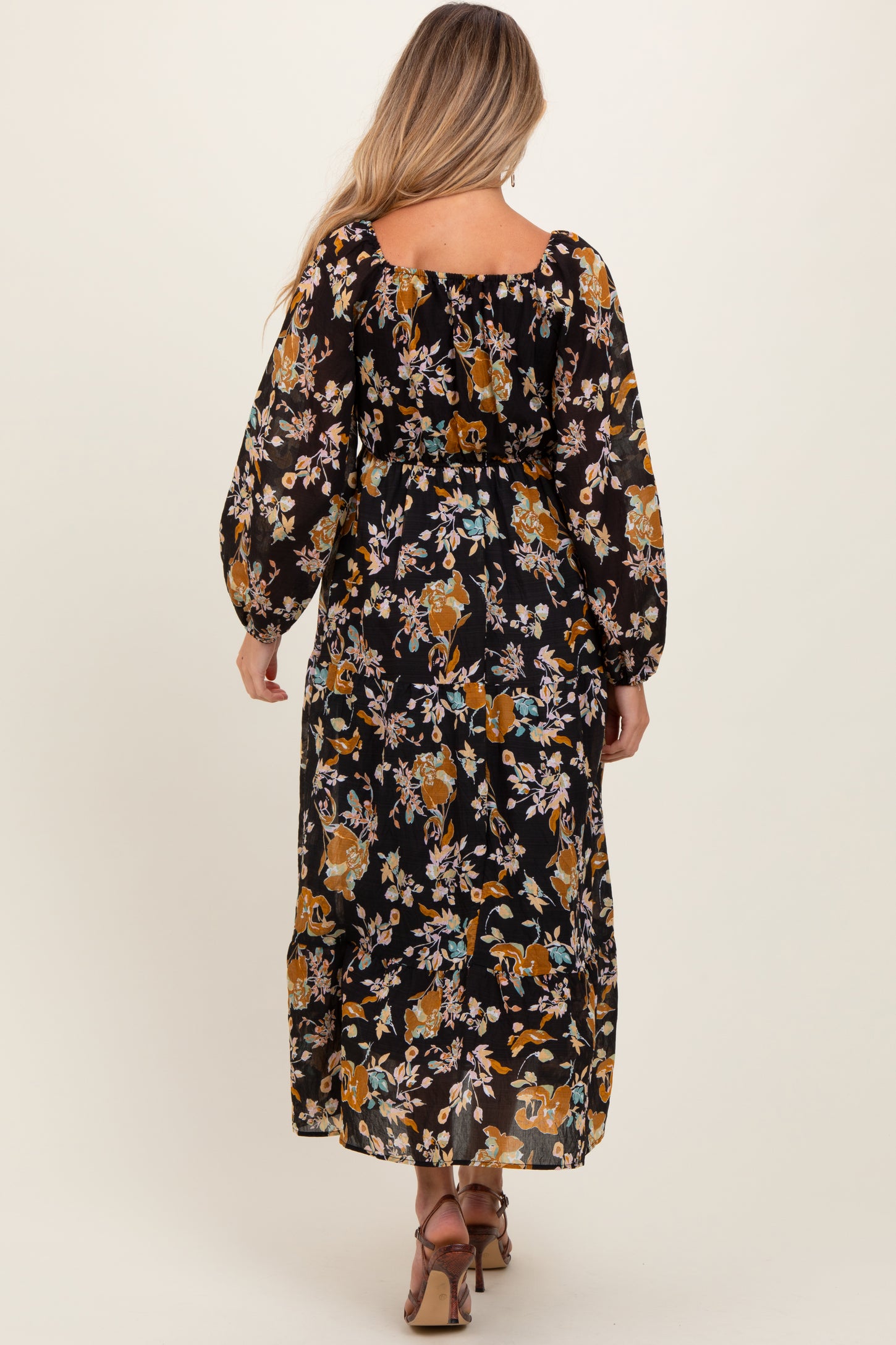woman wearing a black floral maternity maxi dress with long puffed sleeves and a relaxed fit