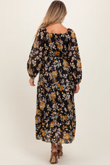woman wearing a black floral maternity maxi dress with long puffed sleeves and a relaxed fit