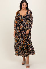 woman wearing a black floral maxi dress with long sleeves and a scoop neckline, smiling while standing