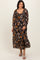 woman wearing a black floral maxi dress with long sleeves and a scoop neckline, smiling while standing