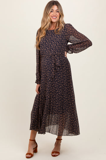 woman wearing a navy blue floral long sleeve maternity dress with a tie waist and flowy skirt