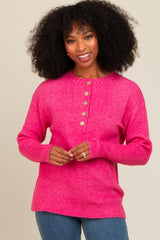 woman wearing a bright pink ribbed sweater with button details and long sleeves, smiling at the camera