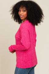 woman wearing a bright pink ribbed sweater, styled with a relaxed fit and round neckline, paired with denim jeans