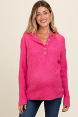 woman wearing a bright pink ribbed maternity sweater with button details and a visible baby bump
