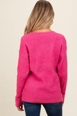 woman wearing a bright pink ribbed maternity sweater, seen from the back, paired with dark blue jeans