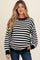 woman wearing a black and white striped maternity sweater with a relaxed fit and visible baby bump