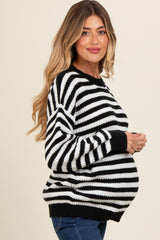 woman wearing a black and white striped maternity sweater and holding her baby bump