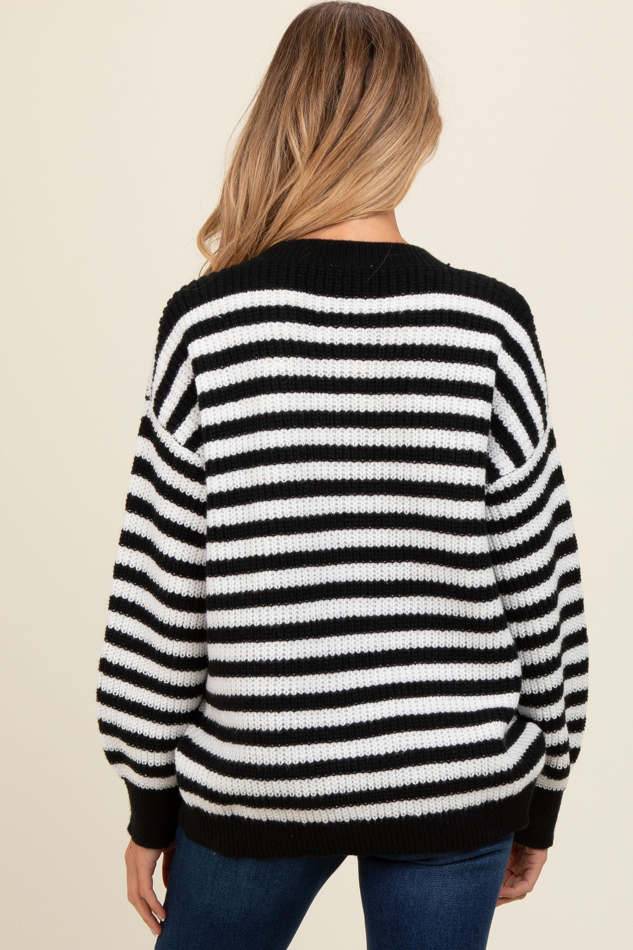 woman wearing a black and white striped oversized maternity sweater, showing the back view