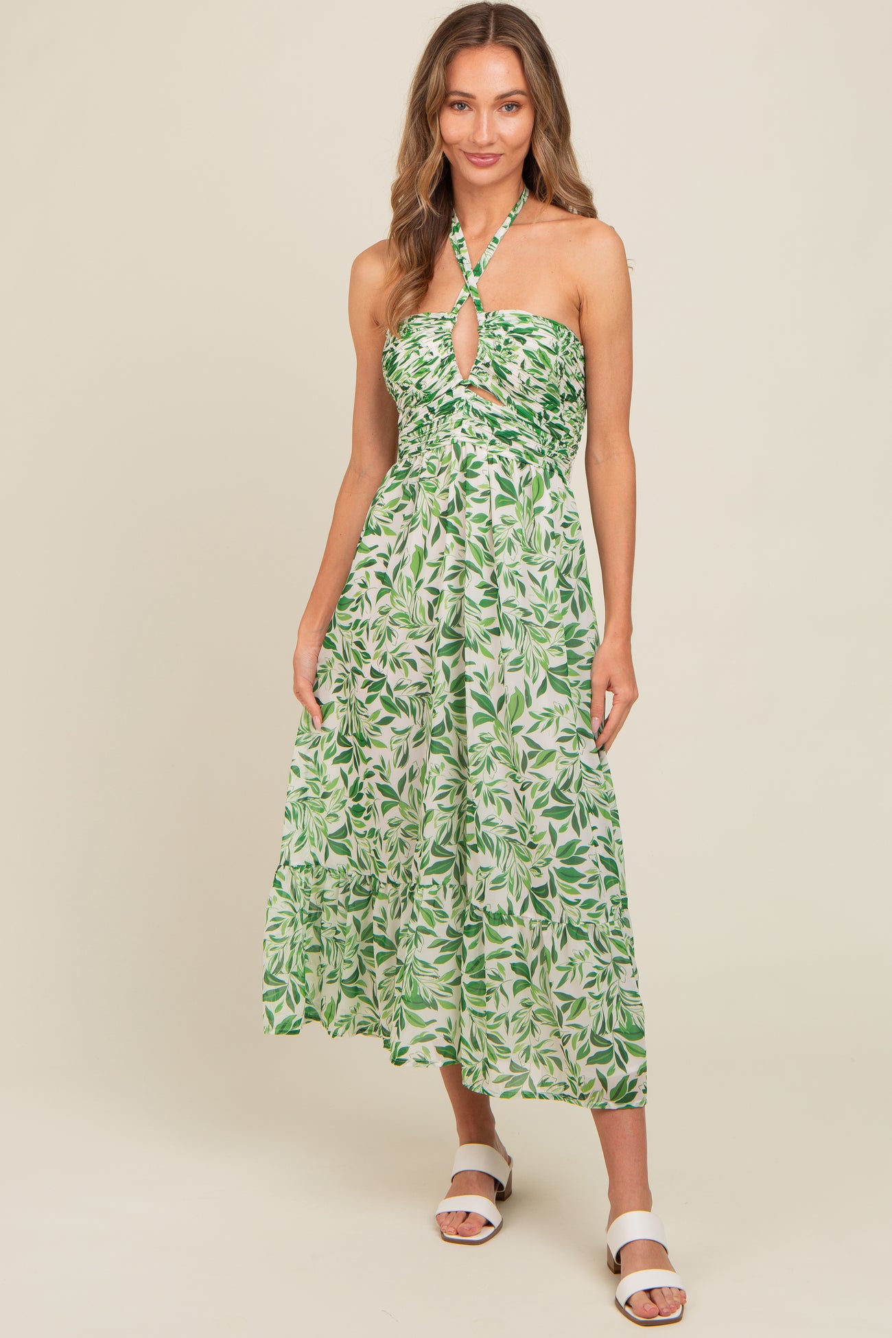 woman wearing a green leaf print halter neck midi dress with a keyhole detail and a flowy skirt