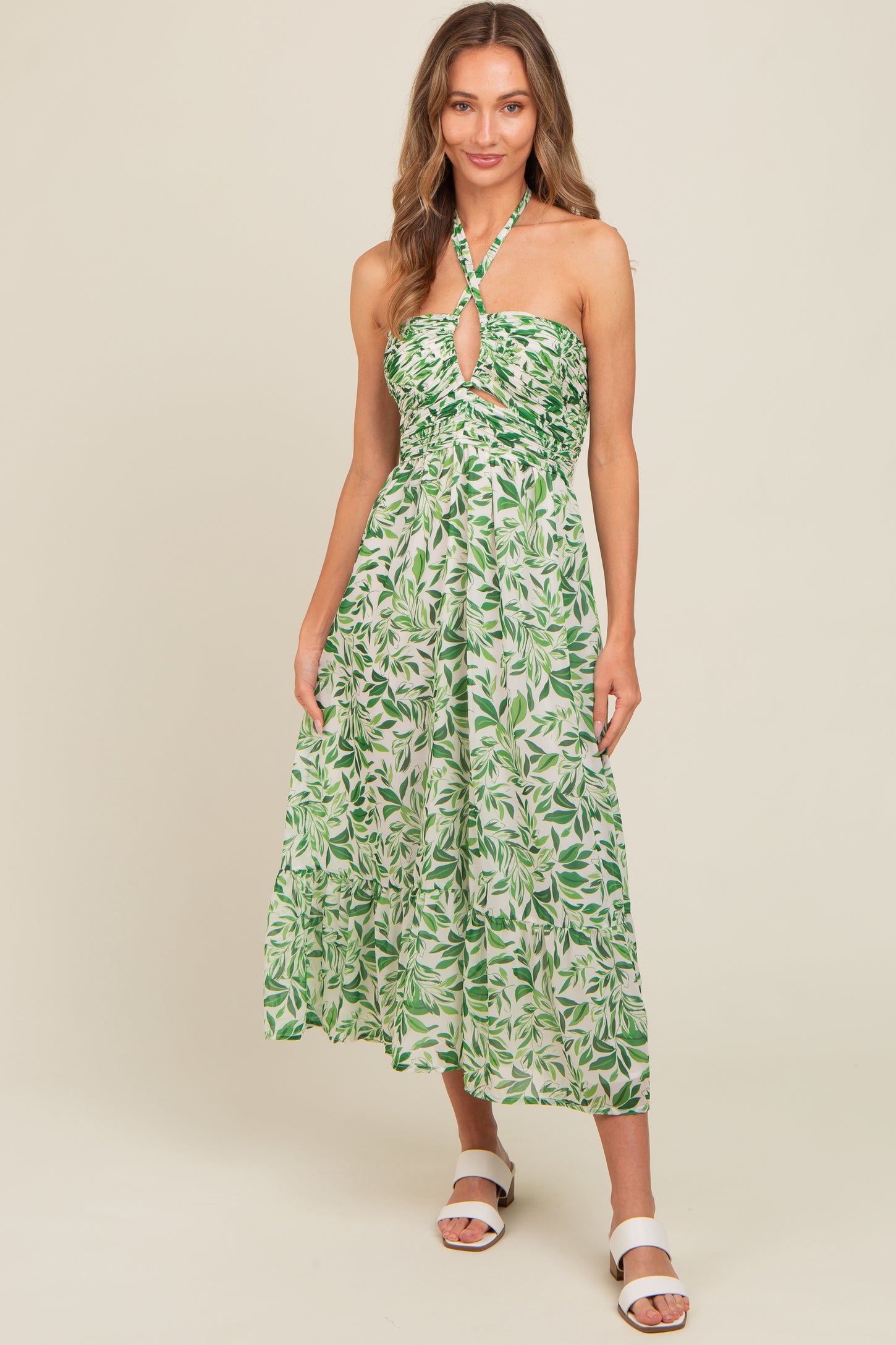 woman wearing a green leaf print halter neck midi dress with a keyhole detail and a flowy skirt