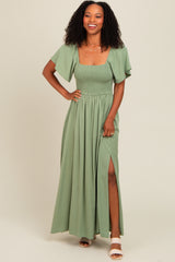 woman wearing a long green maxi dress with a smocked bodice and flutter sleeves, featuring a side slit