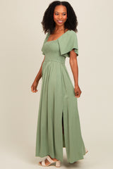 woman wearing a light green maxi dress with a smocked bodice and short sleeves, featuring a side slit