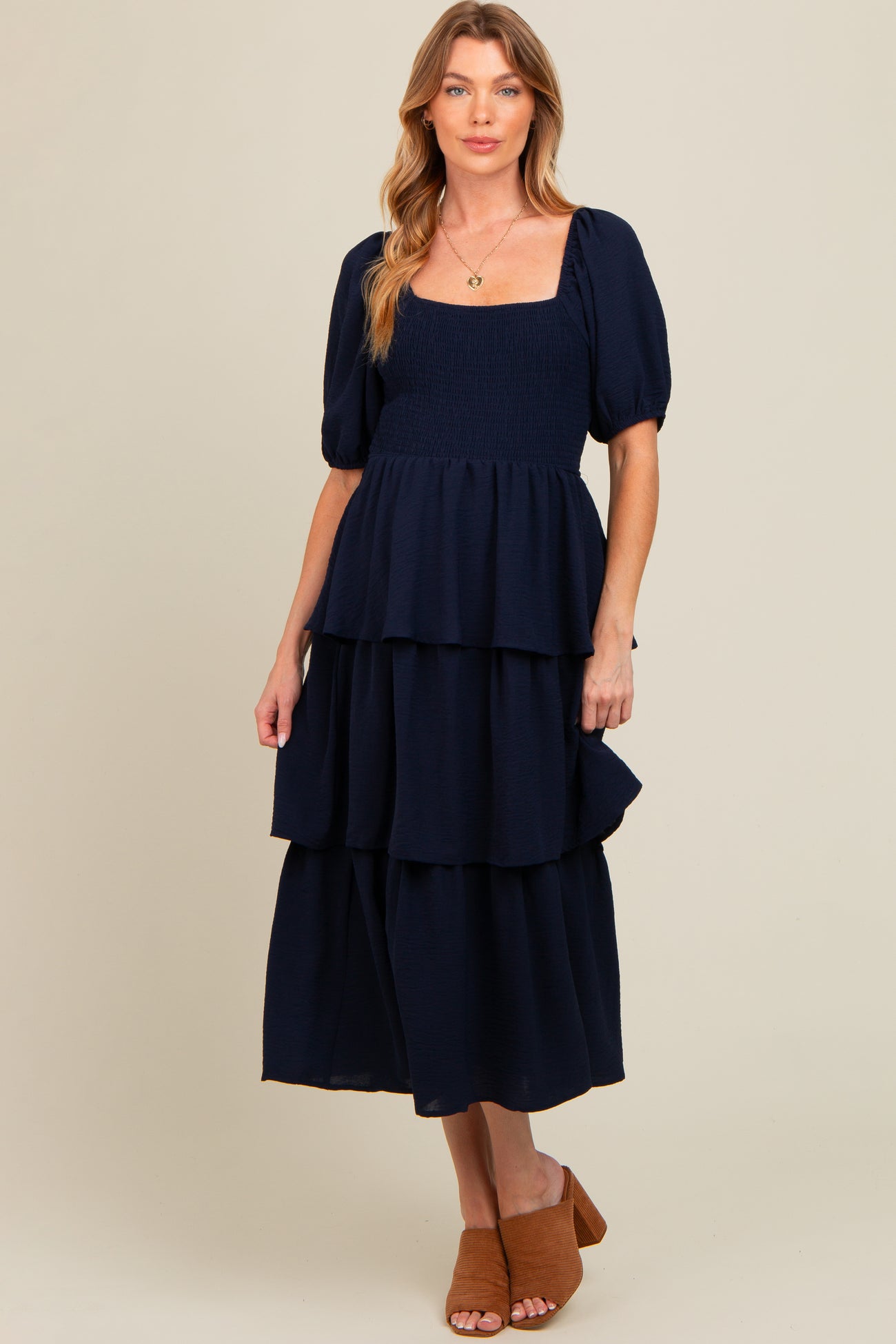 woman wearing a navy blue maternity tiered maxi dress with puff sleeves and a square neckline