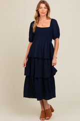 woman wearing a navy blue maternity tiered maxi dress with puff sleeves and a square neckline